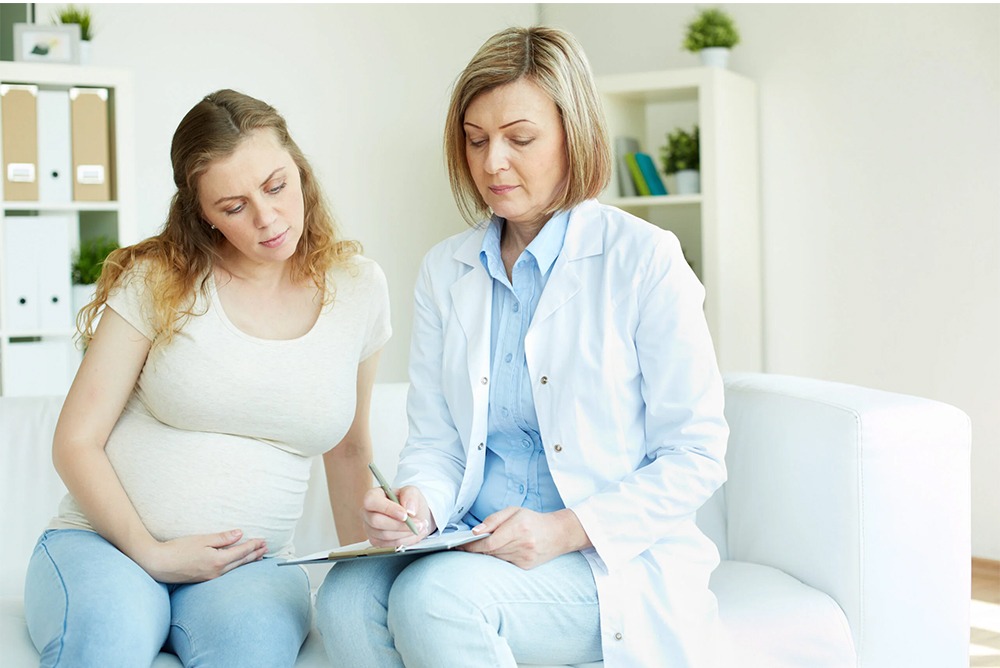 Young pregnant woman listening to prescription of doctor after regular examination at hospital